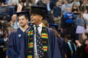 A UNC Asheville graduate smiling during commencement ceremony.