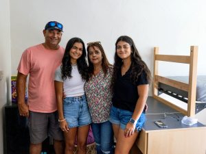 Student and parents standing in residence hall room unpacking during August 2023 Move-In.