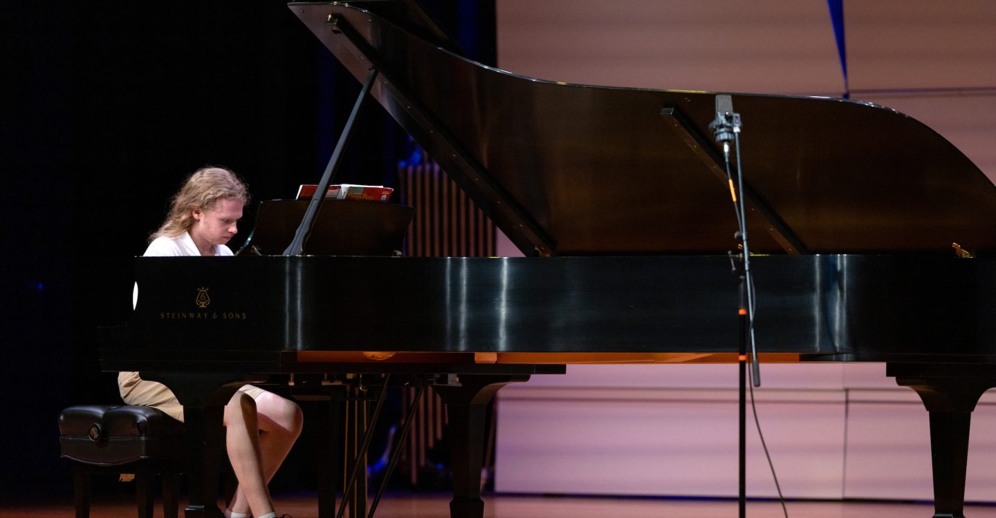 someone playing a grand piano onstage in Lipinsky Hall