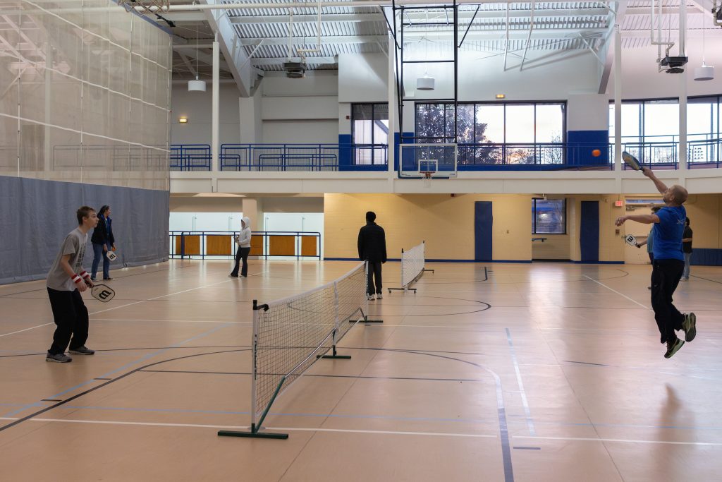 multiple people playing pickleball on an indoor court